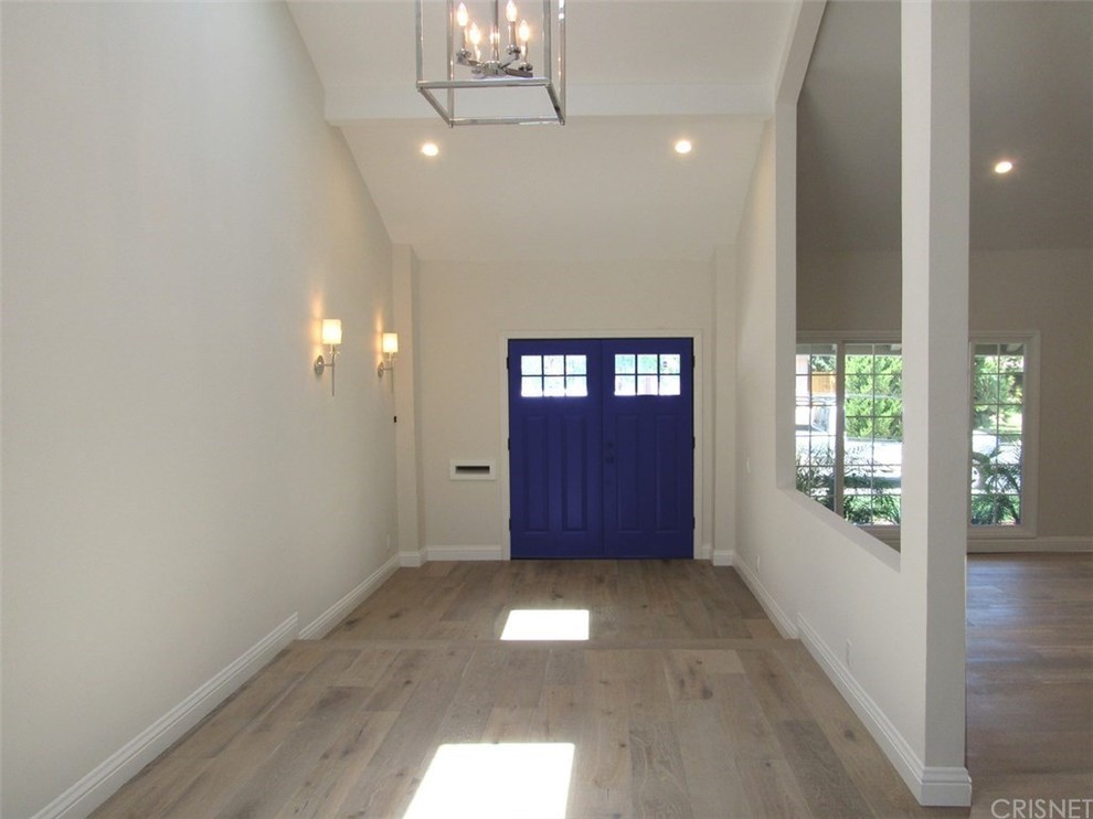 ロサンゼルスにあるお手頃価格の広いトランジショナルスタイルのおしゃれな玄関ドア (白い壁、無垢フローリング、青いドア) の写真