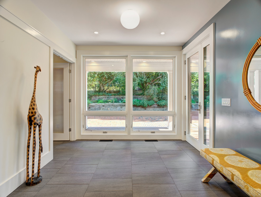 Réalisation d'une grande porte d'entrée design avec un mur blanc, un sol en carrelage de porcelaine, une porte bleue et un sol gris.