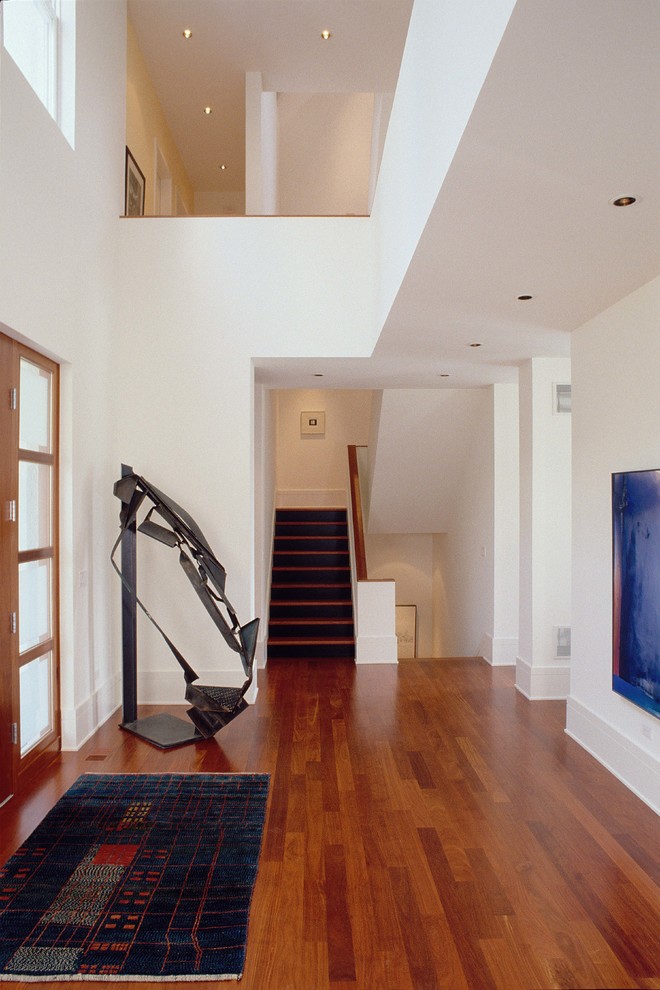 Inspiration pour un hall d'entrée minimaliste de taille moyenne avec un mur blanc, une porte simple, un sol en bois brun, une porte en bois brun et un sol marron.