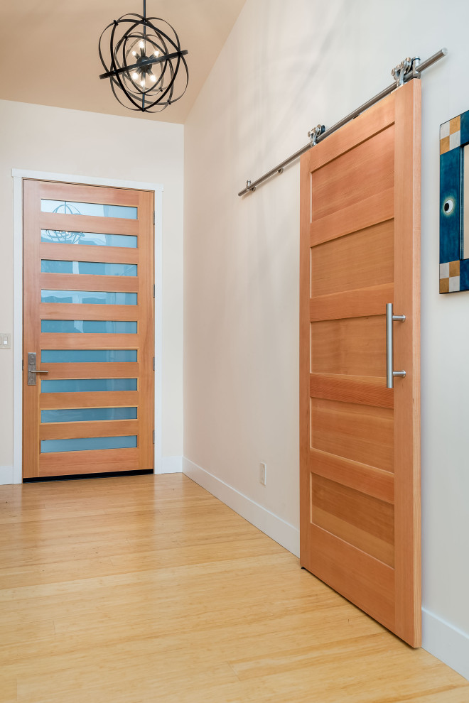 Diseño de puerta principal blanca retro grande con paredes blancas, suelo de madera clara, puerta simple, puerta de madera clara y suelo marrón
