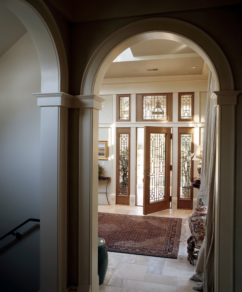 アトランタにある広いトラディショナルスタイルのおしゃれな玄関ロビー (白い壁、ライムストーンの床、木目調のドア) の写真