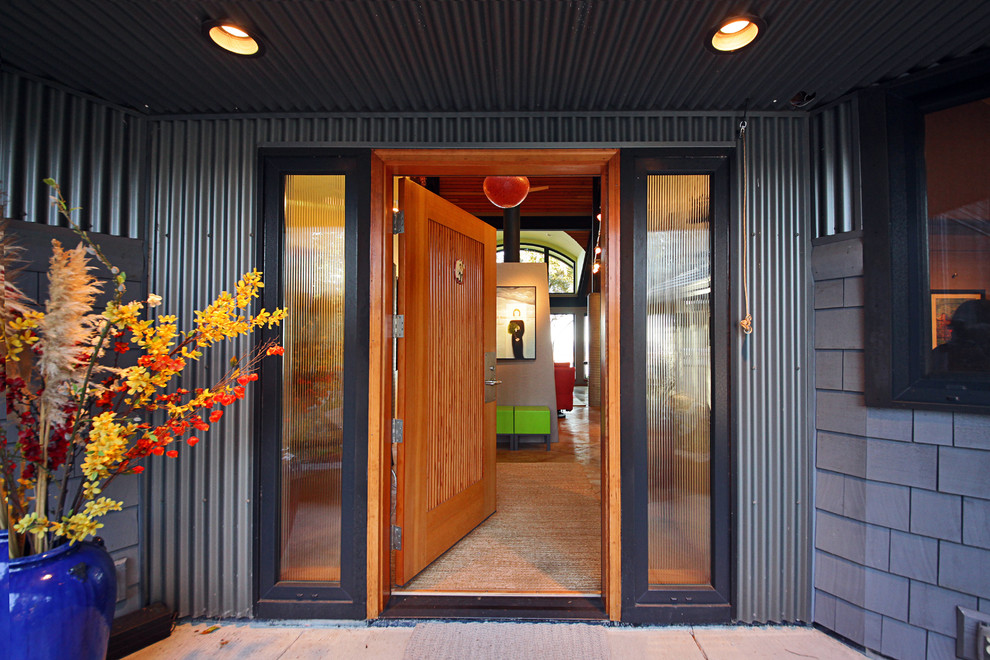 Foto på en mellanstor industriell ingång och ytterdörr, med grå väggar, betonggolv, en enkeldörr och ljus trädörr