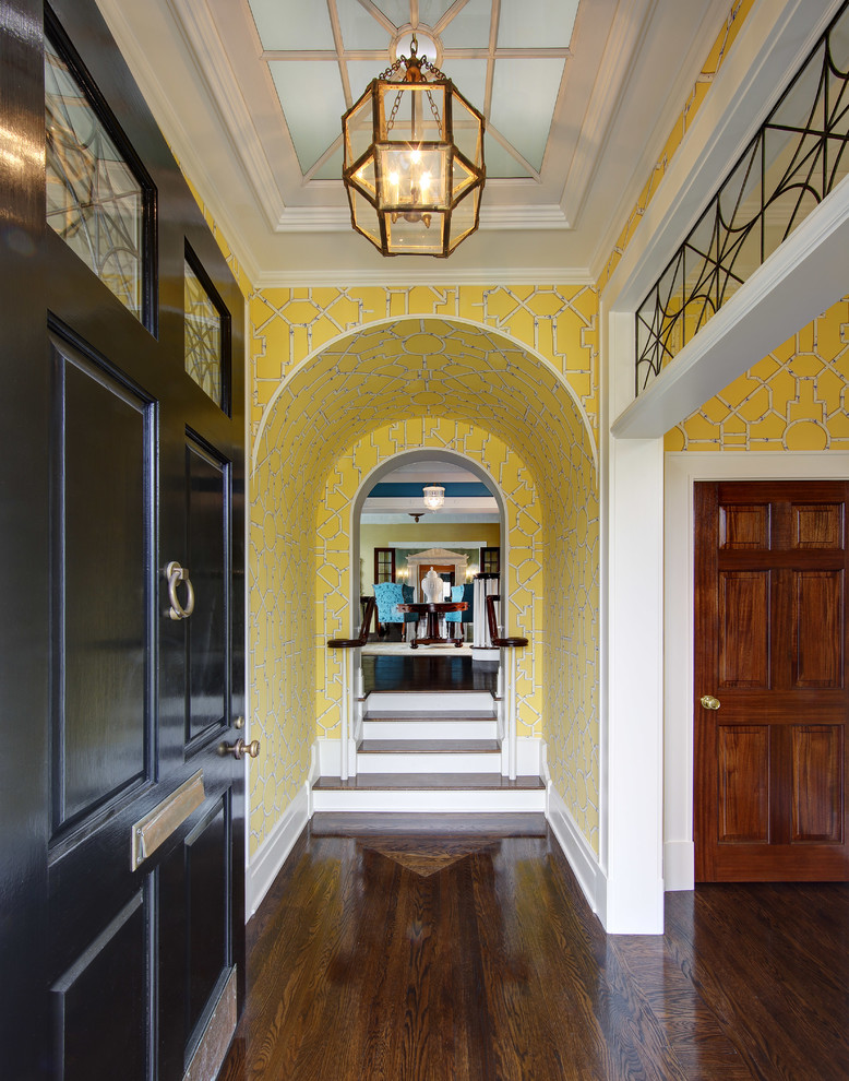 На фото: прихожая в классическом стиле с желтыми стенами, темным паркетным полом, одностворчатой входной дверью и черной входной дверью