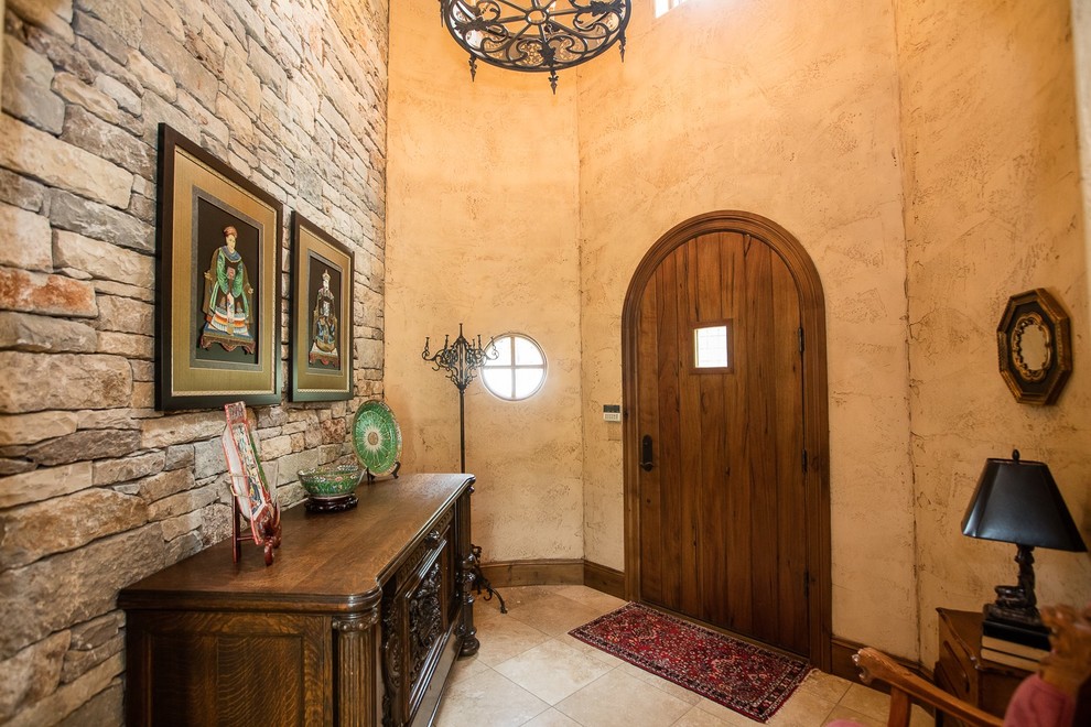 Klassisk inredning av en mycket stor foajé, med beige väggar, kalkstensgolv, en enkeldörr, en brun dörr och beiget golv