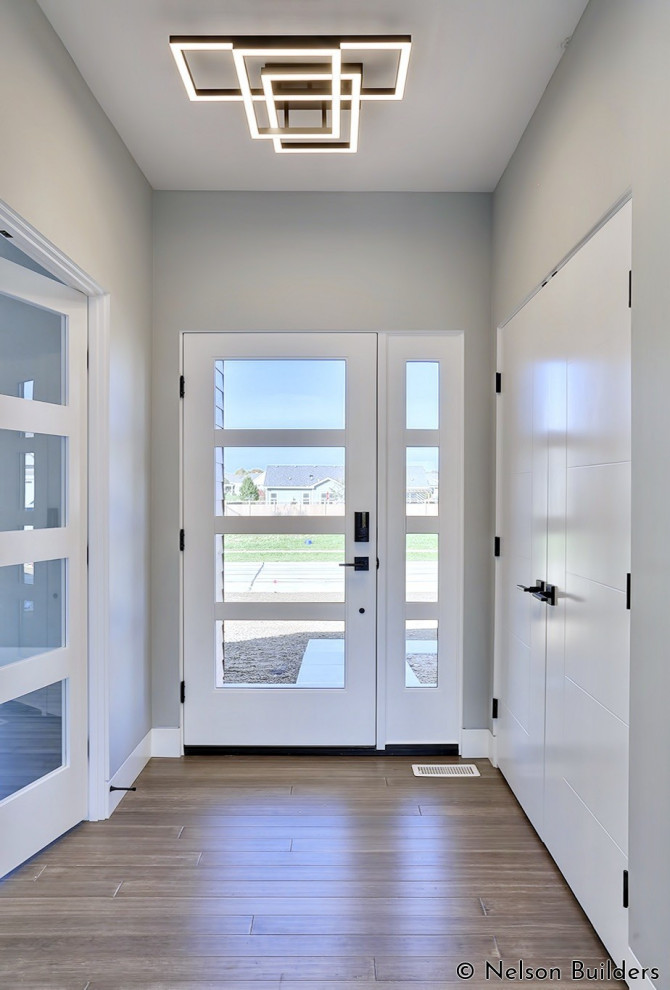 Inspiration pour un petit hall d'entrée minimaliste avec un mur gris, parquet en bambou, une porte simple, une porte en verre et un sol marron.