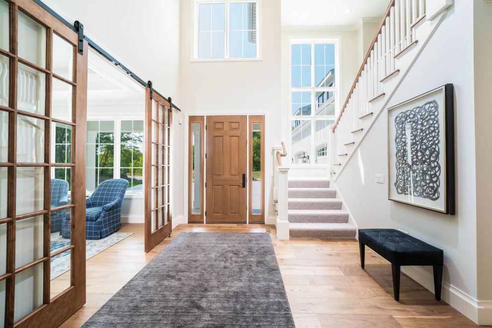 Modelo de entrada de estilo de casa de campo con paredes blancas, suelo de madera en tonos medios, puerta simple y puerta de madera en tonos medios