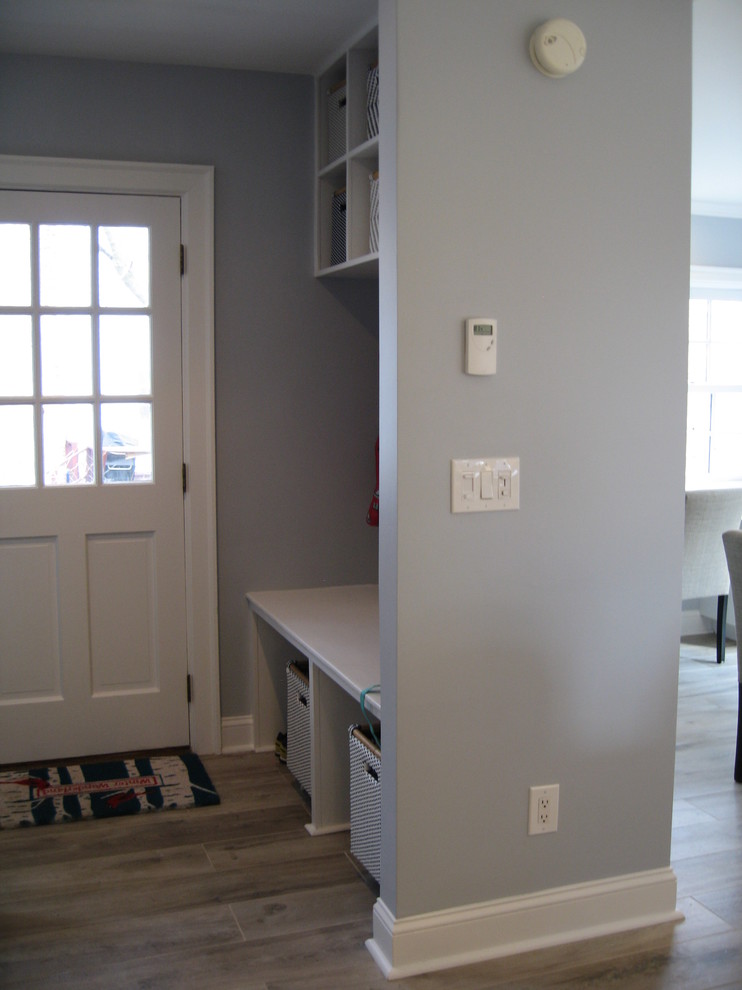 Aménagement d'une entrée classique de taille moyenne avec un couloir, un mur gris, un sol en carrelage de porcelaine, une porte simple, une porte blanche et un sol marron.