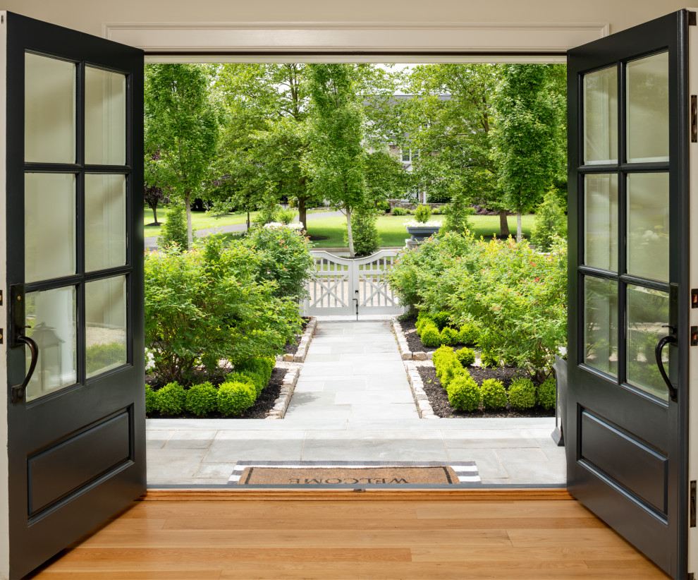Idee per un grande ingresso chic con pareti beige, pavimento in legno massello medio, una porta a due ante, una porta nera e pavimento marrone