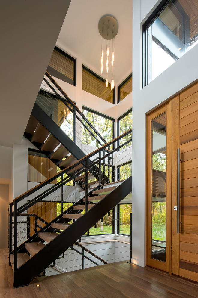 Ispirazione per una porta d'ingresso minimalista di medie dimensioni con pareti bianche, pavimento in legno massello medio, una porta in legno bruno, pavimento marrone e una porta a pivot