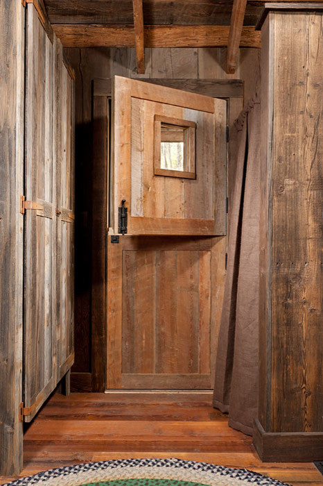 Réalisation d'une petite porte d'entrée chalet avec un mur marron, un sol en bois brun, une porte hollandaise et une porte en bois brun.