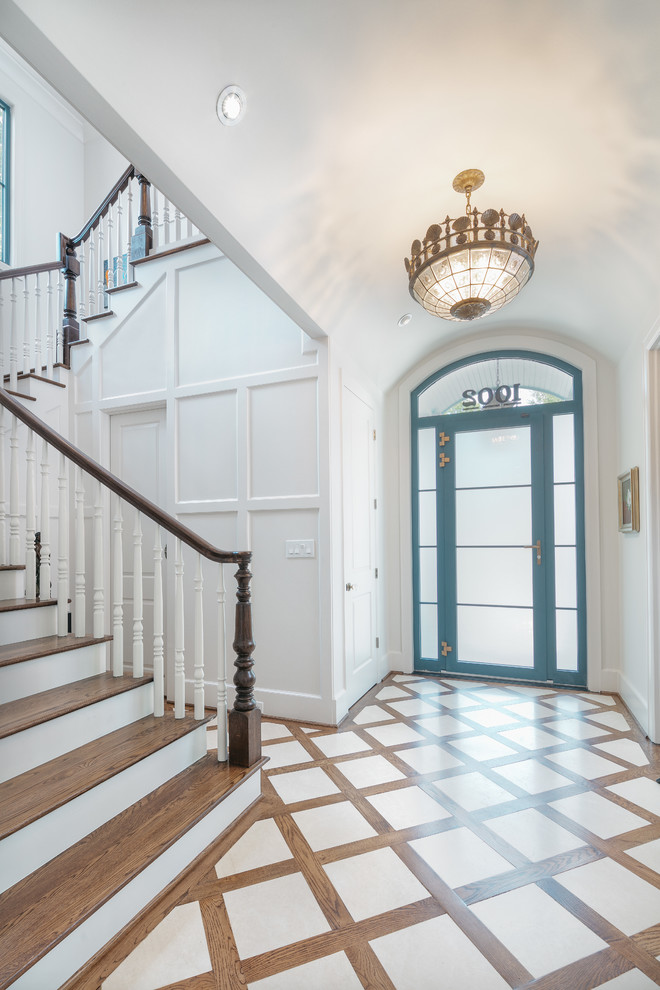 На фото: огромное фойе в стиле неоклассика (современная классика) с белыми стенами, полом из керамической плитки, одностворчатой входной дверью, синей входной дверью и разноцветным полом с