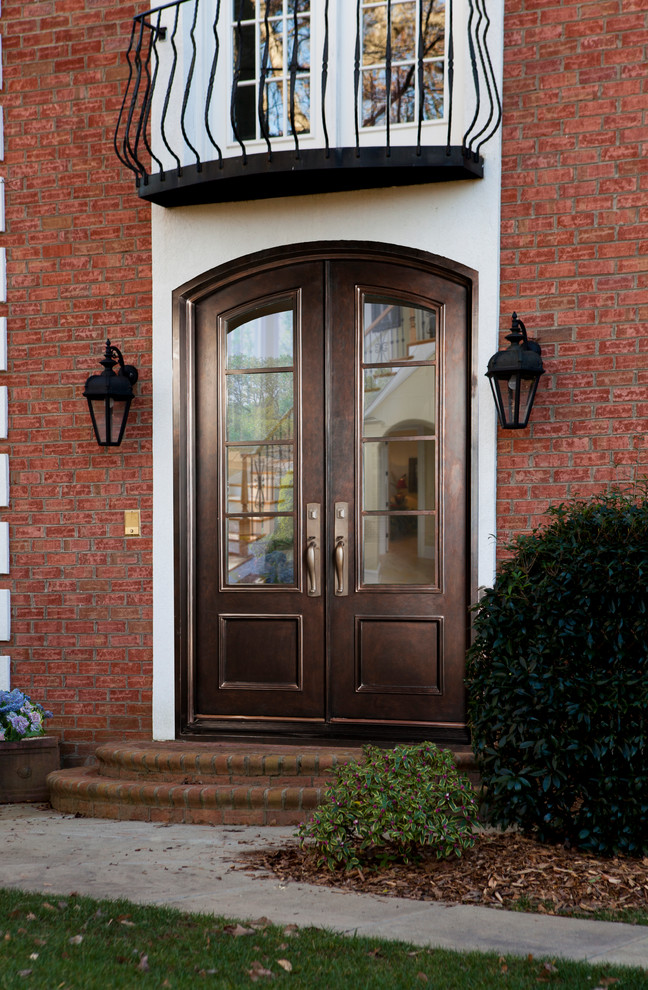 На фото: большая входная дверь: освещение с двустворчатой входной дверью, коричневыми стенами, коричневой входной дверью и кирпичными стенами
