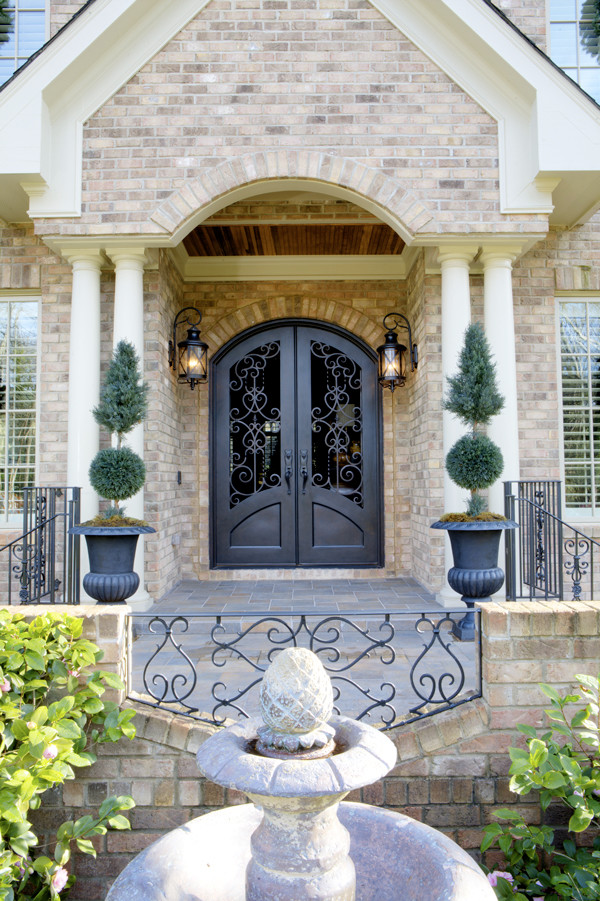 This is an example of a large traditional front door in Charlotte with a double front door, a black front door and feature lighting.