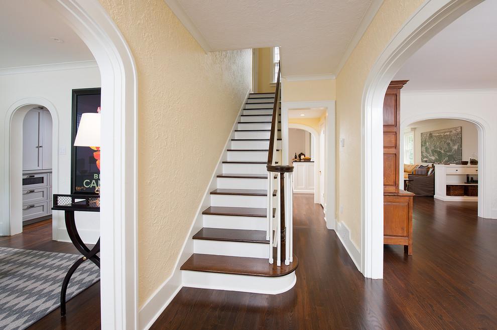 Cette image montre une grande entrée craftsman avec un couloir, un mur beige, parquet foncé, une porte simple et un sol marron.
