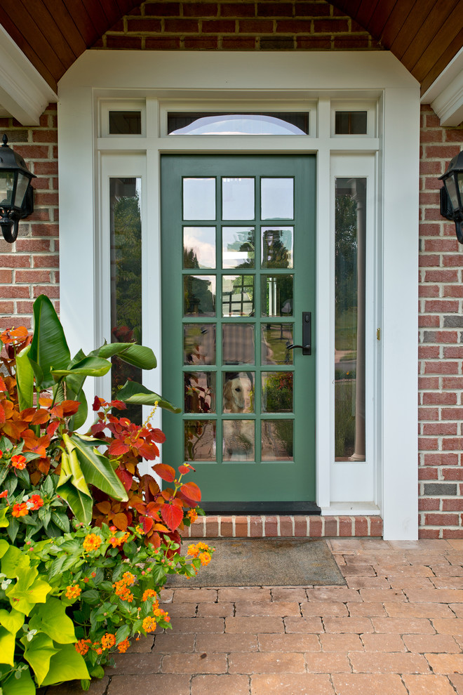 Cette image montre une grande porte d'entrée traditionnelle avec une porte simple et une porte verte.