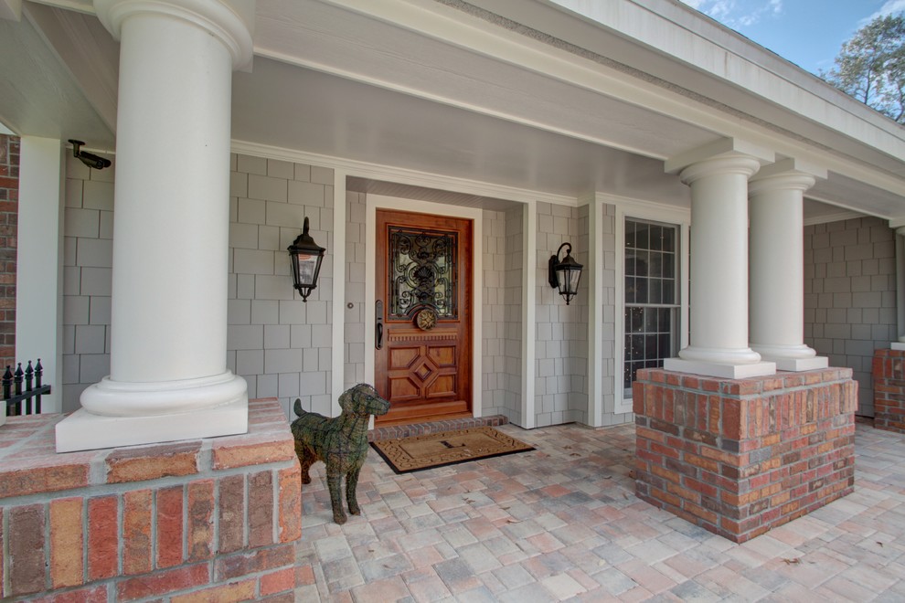 Immagine di una grande porta d'ingresso classica con una porta singola, una porta in legno bruno, pareti grigie, pavimento in mattoni e pavimento multicolore