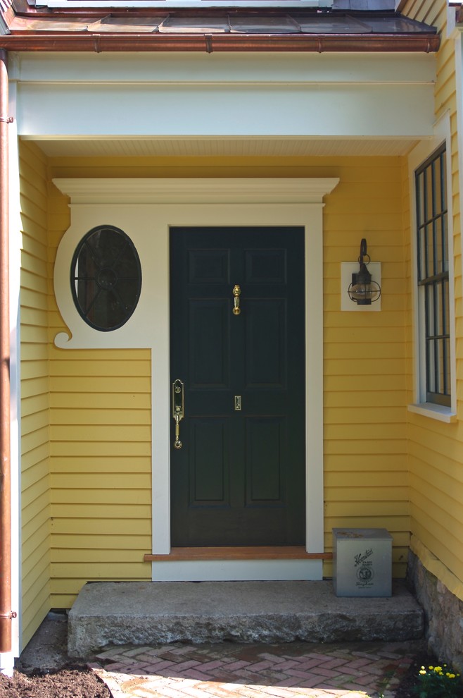 На фото: входная дверь в классическом стиле с желтыми стенами, гранитным полом, одностворчатой входной дверью и серой входной дверью с