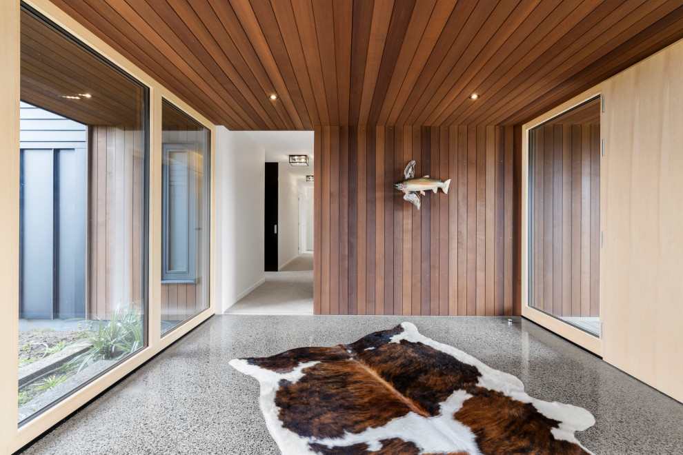Идея дизайна: большая входная дверь в стиле рустика с коричневыми стенами, бетонным полом, поворотной входной дверью, входной дверью из светлого дерева, серым полом, потолком из вагонки и деревянными стенами
