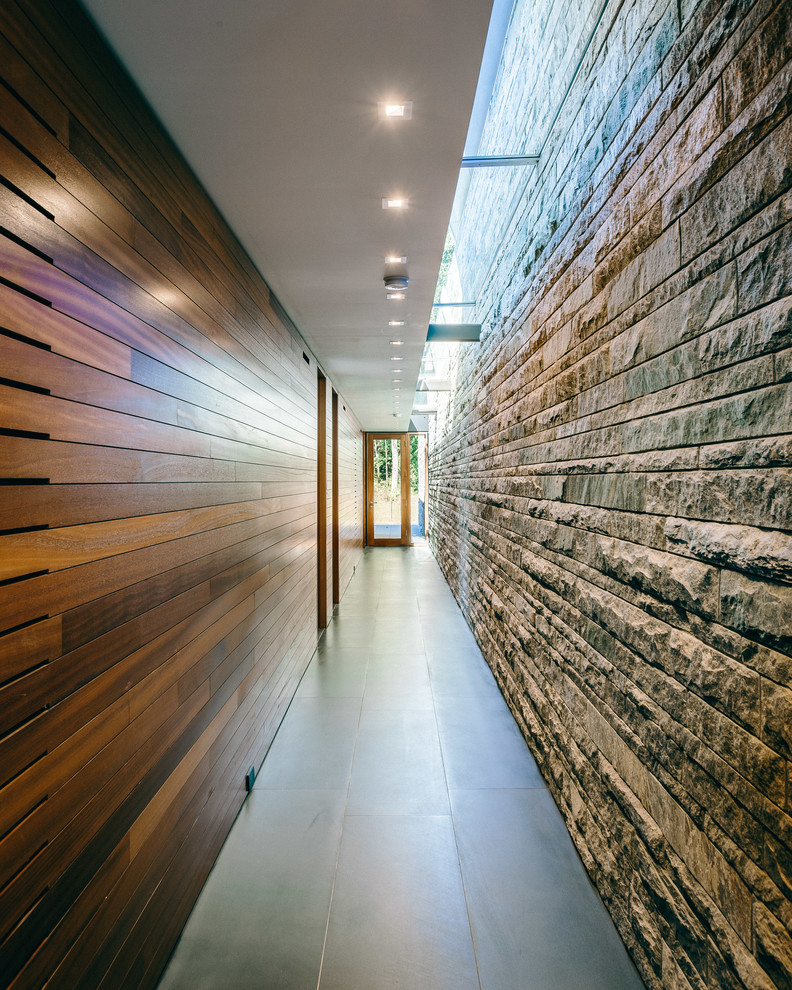 Cette photo montre un grand couloir moderne avec un mur marron, sol en béton ciré et un sol gris.