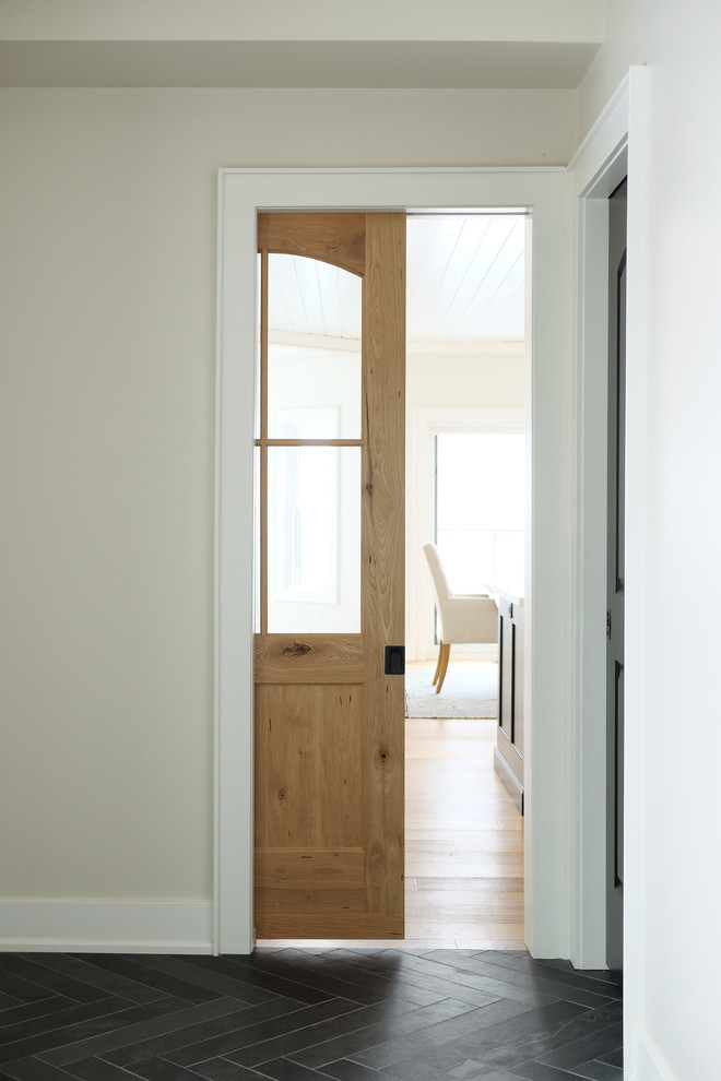 Exemple d'une entrée nature de taille moyenne avec un vestiaire, un mur blanc, une porte simple, une porte en bois brun et un sol gris.