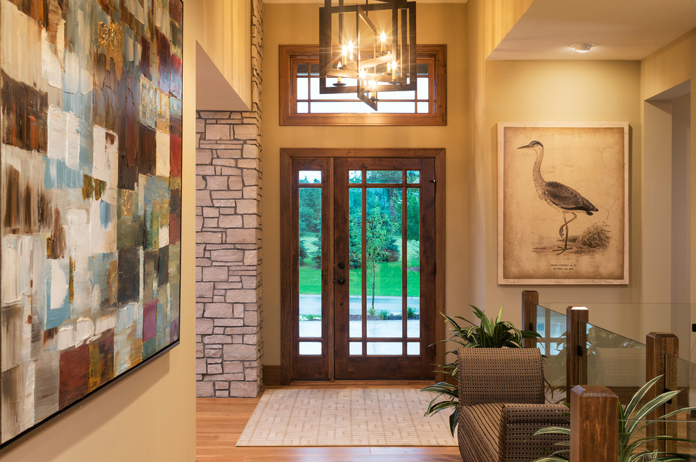 Immagine di un grande ingresso minimal con pareti beige, pavimento in legno massello medio, una porta singola e una porta in vetro
