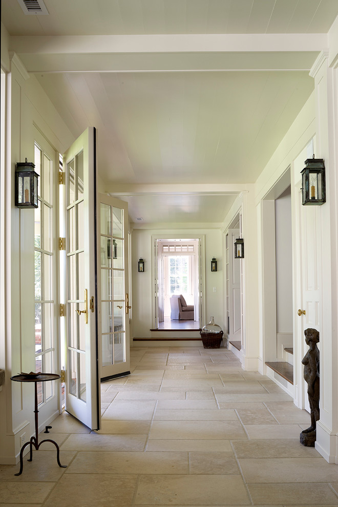 На фото: узкая прихожая в классическом стиле с белыми стенами, двустворчатой входной дверью, стеклянной входной дверью и полом из травертина с