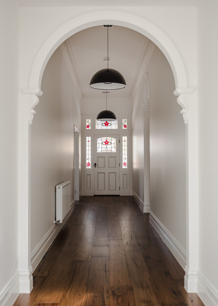 На фото: узкая прихожая в стиле неоклассика (современная классика) с белыми стенами, паркетным полом среднего тона, одностворчатой входной дверью, белой входной дверью и коричневым полом