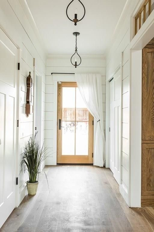 Foto di un ingresso country di medie dimensioni con pareti bianche, parquet chiaro, una porta a pivot, una porta in legno chiaro e pavimento marrone