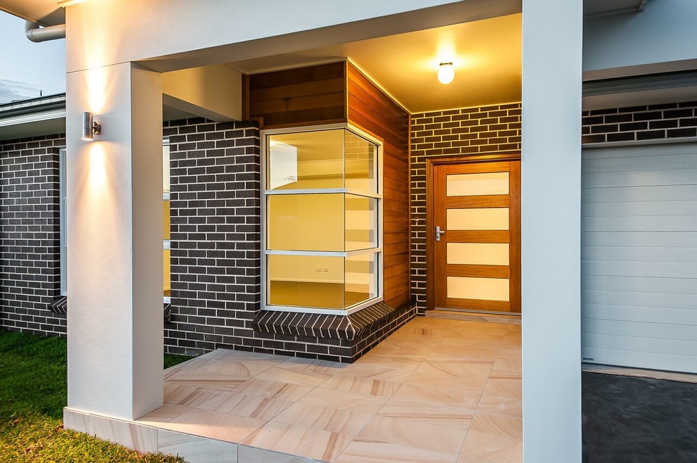 Foto di una porta d'ingresso minimalista di medie dimensioni con pareti marroni, pavimento in pietra calcarea, una porta a pivot e una porta in legno bruno