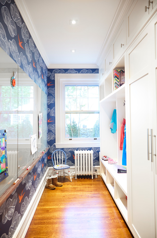 Inspiration pour une petite entrée traditionnelle avec un vestiaire, un mur bleu, un sol en bois brun et un sol marron.