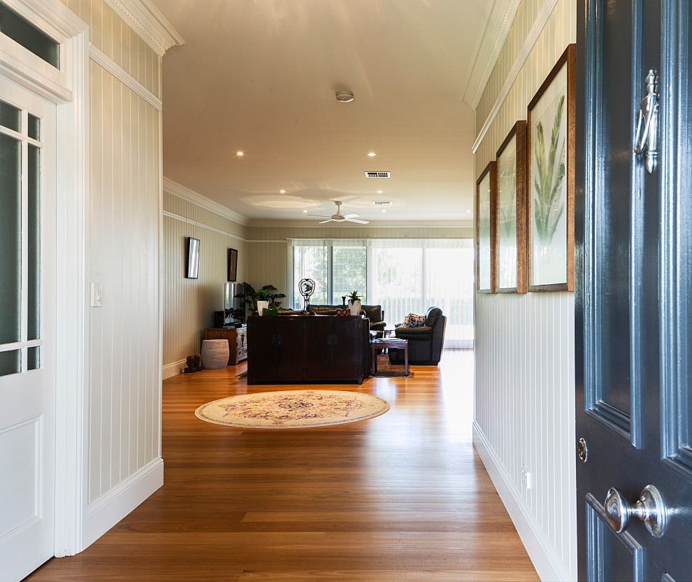 Example of a huge eclectic light wood floor and orange floor entryway design in Brisbane with white walls and a blue front door