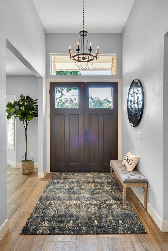 Idées déco pour un hall d'entrée classique de taille moyenne avec un mur gris, un sol en bois brun, une porte double, une porte en bois foncé et un sol marron.