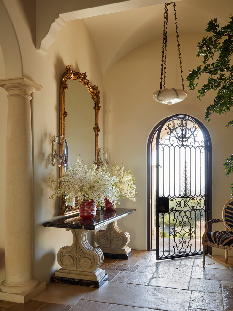 Ejemplo de puerta principal mediterránea con paredes beige, suelo de piedra caliza, puerta simple y suelo beige