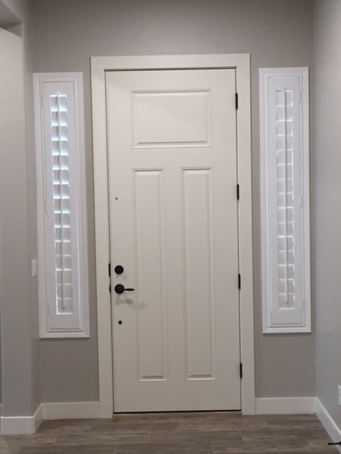 Idee per una piccola porta d'ingresso chic con pareti grigie, pavimento in legno massello medio, una porta singola, una porta bianca e pavimento marrone