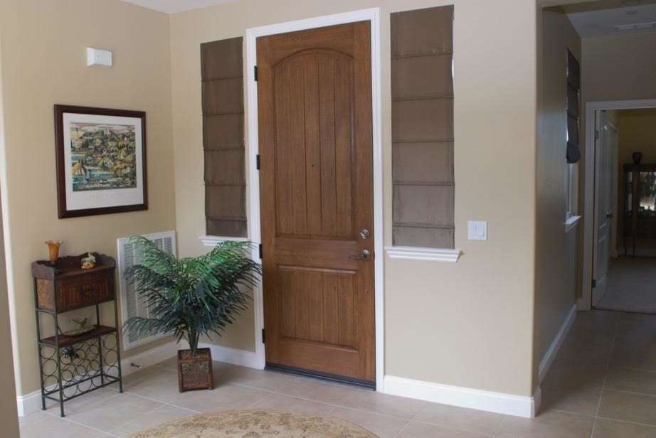 Cette image montre une entrée traditionnelle de taille moyenne avec un mur beige, un sol en carrelage de céramique, une porte simple et une porte en bois foncé.