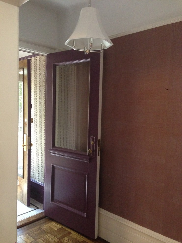 Modern inredning av en liten foajé, med lila väggar, marmorgolv, en enkeldörr och en lila dörr