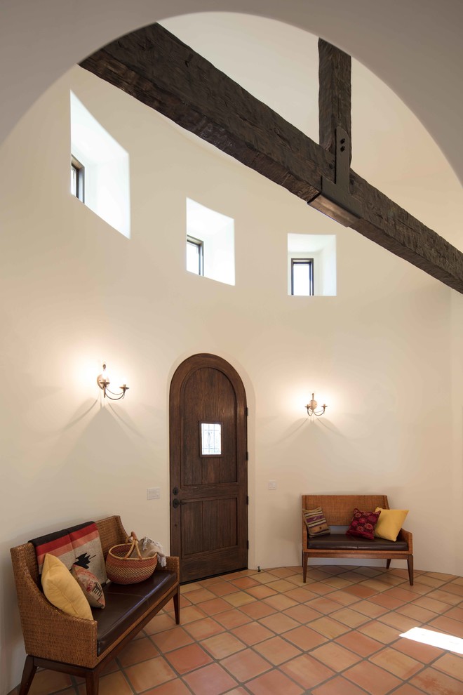 Inredning av en medelhavsstil stor foajé, med vita väggar, en enkeldörr, mörk trädörr, klinkergolv i terrakotta och orange golv