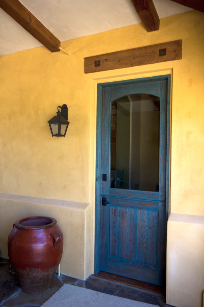 サンルイスオビスポにある中くらいなラスティックスタイルのおしゃれな玄関ドア (黄色い壁、セラミックタイルの床、青いドア) の写真