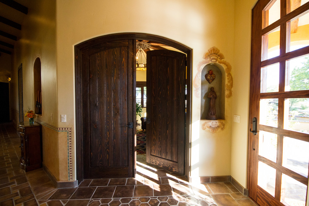 サンルイスオビスポにある巨大なラスティックスタイルのおしゃれな玄関ドア (濃色木目調のドア、黄色い壁、セラミックタイルの床) の写真
