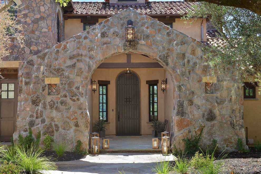 На фото: входная дверь в средиземноморском стиле с одностворчатой входной дверью и коричневой входной дверью