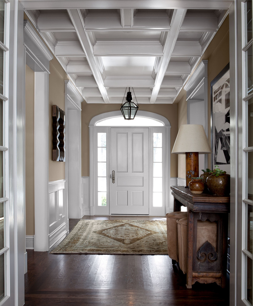 Imagen de distribuidor clásico de tamaño medio con paredes beige, suelo de madera oscura, puerta simple y puerta blanca
