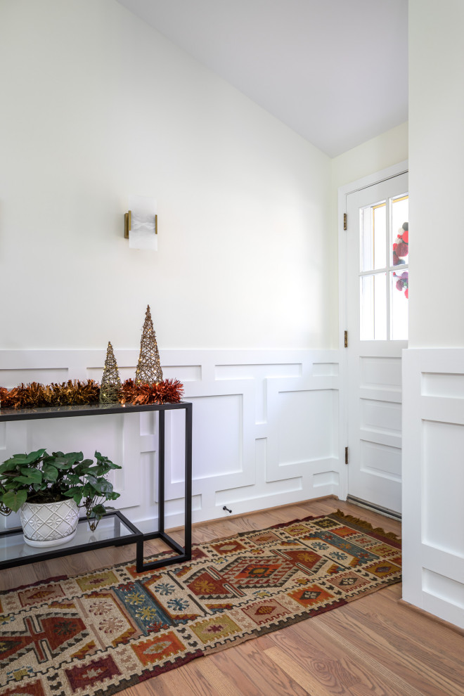 Inspiration pour un hall d'entrée traditionnel de taille moyenne avec un mur blanc, un sol en bois brun, une porte simple, une porte en verre, un sol marron et boiseries.
