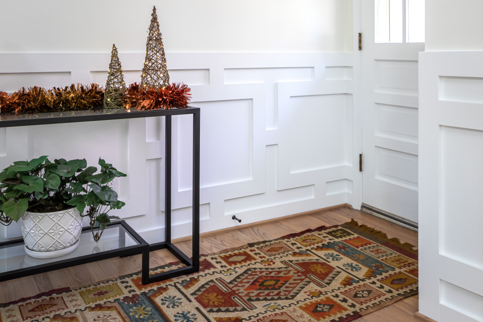 Mid-sized transitional medium tone wood floor, brown floor and wainscoting entryway photo in Raleigh with white walls and a glass front door