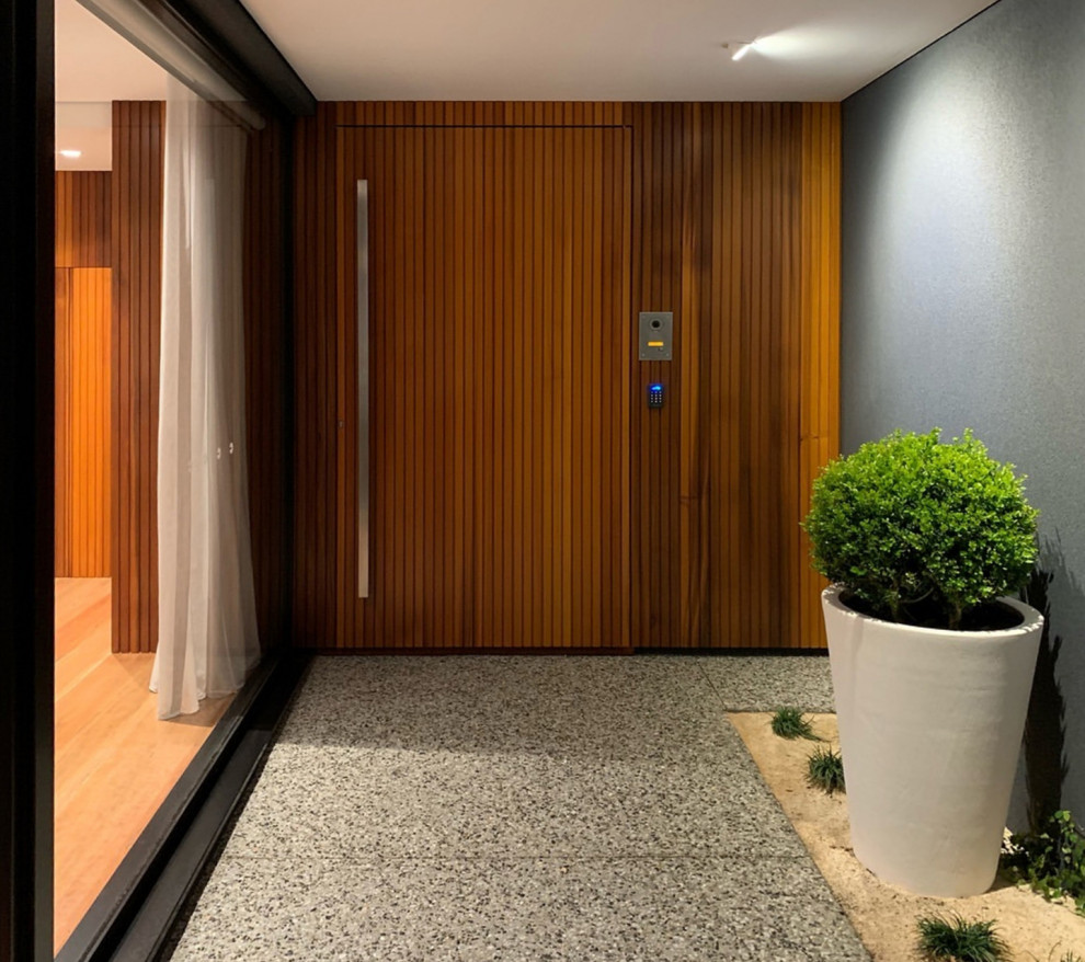 Imagen de puerta principal blanca contemporánea con puerta de madera en tonos medios, paredes grises, suelo de granito, puerta pivotante y suelo gris