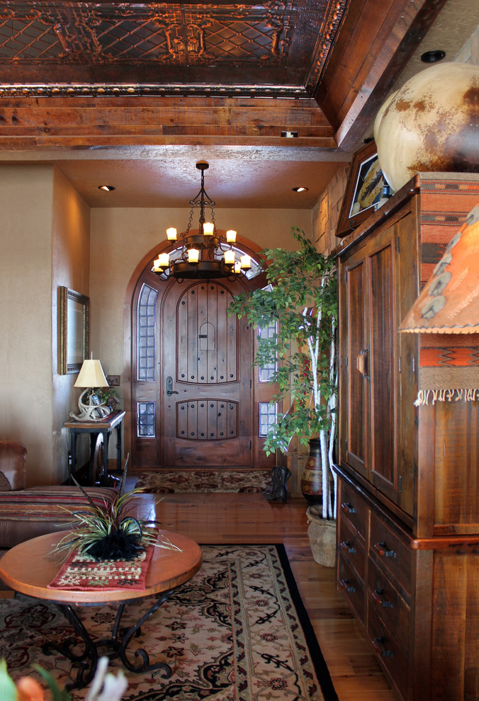 Modelo de vestíbulo posterior de tamaño medio con paredes beige, suelo de madera en tonos medios, puerta simple y puerta de madera en tonos medios