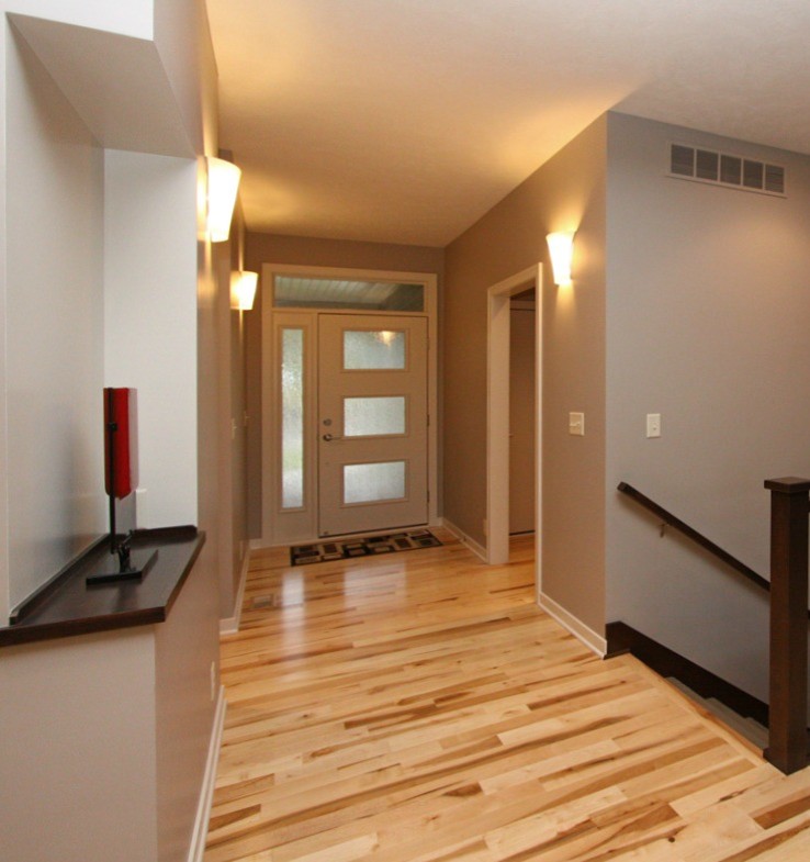 Esempio di un ingresso o corridoio minimalista con pareti grigie, parquet chiaro, una porta singola e una porta bianca