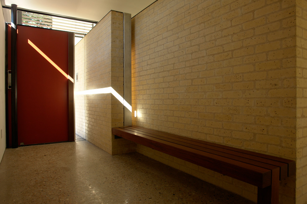 Idée de décoration pour une grande porte d'entrée minimaliste avec un mur beige, une porte simple et une porte rouge.