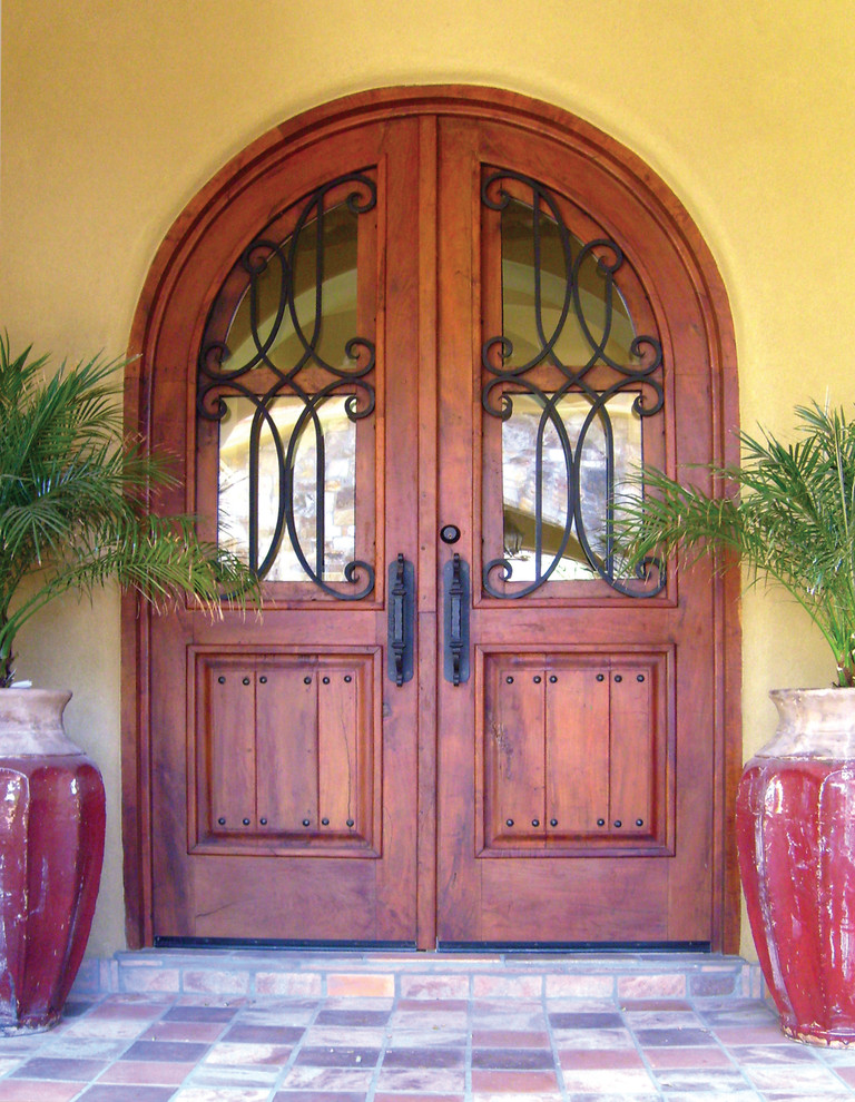 На фото: входная дверь среднего размера в стиле рустика с желтыми стенами, полом из терракотовой плитки, двустворчатой входной дверью и входной дверью из дерева среднего тона с