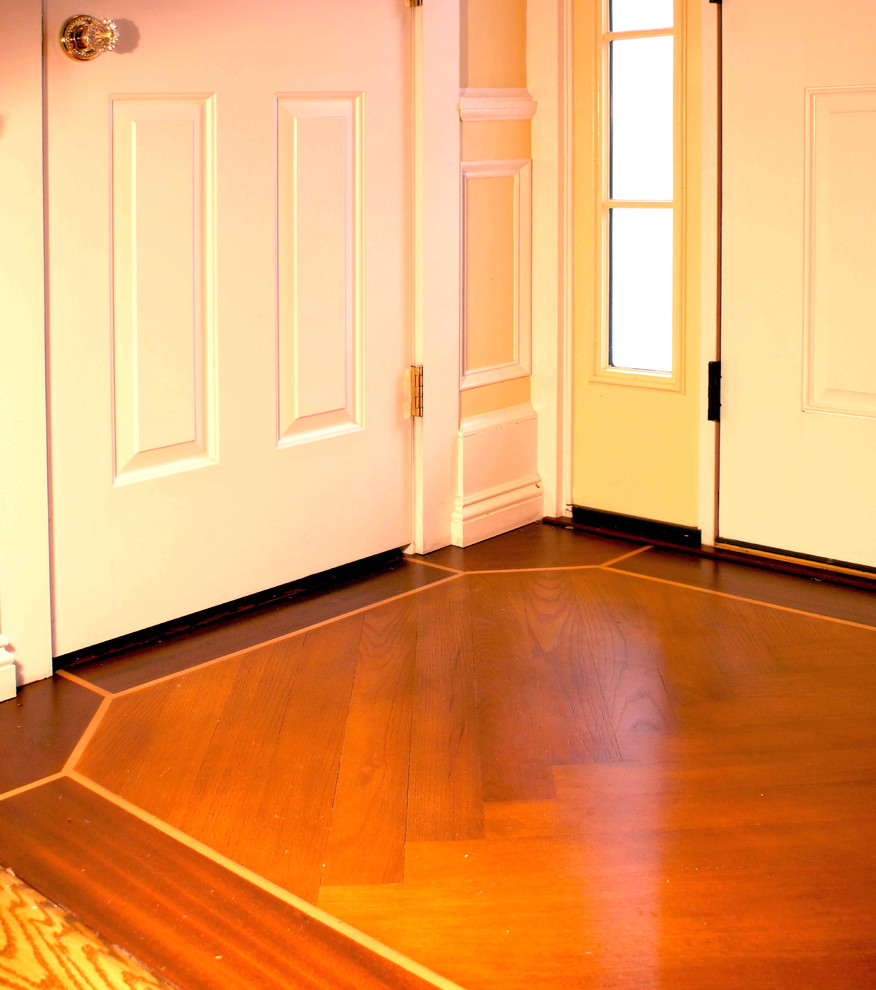 Aménagement d'un hall d'entrée classique de taille moyenne avec un mur jaune, un sol en bois brun, une porte simple et une porte blanche.