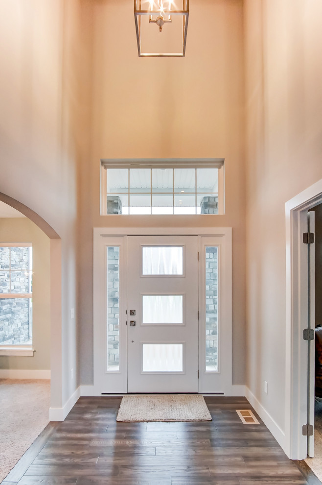 Inredning av en klassisk mellanstor ingång och ytterdörr, med beige väggar, mörkt trägolv, en enkeldörr, en vit dörr och brunt golv